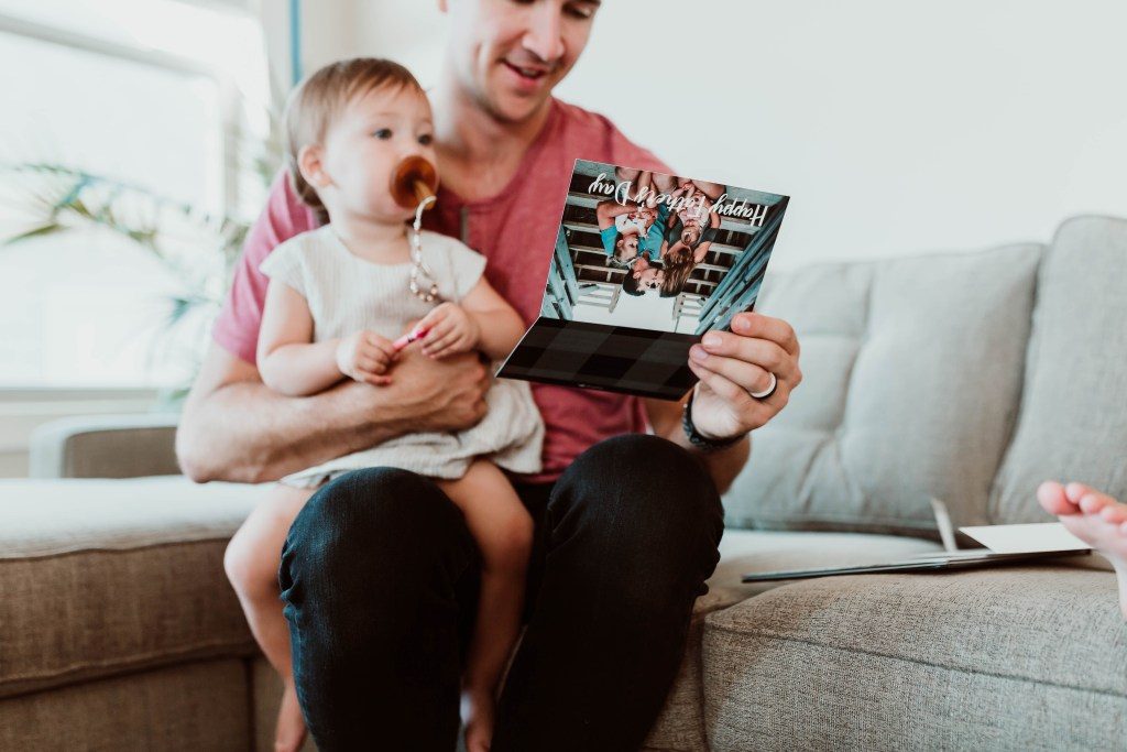 A dad with his child reading a greeting card