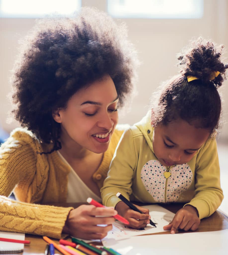 Mother and daughter coloring together at table