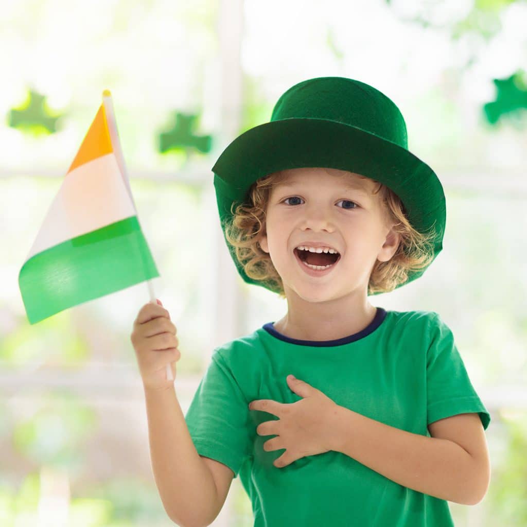 Little boy celebrating St. Patrick's Day while holding an Irish flag