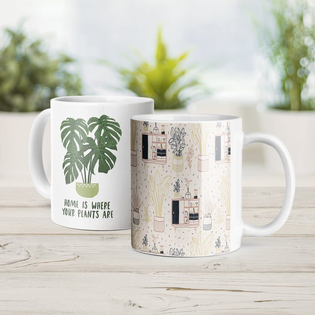 Two white coffee mugs, one saying "Home is where your plants are" with a plant illustration, the other featuring a linework style illustration of home decor and plants