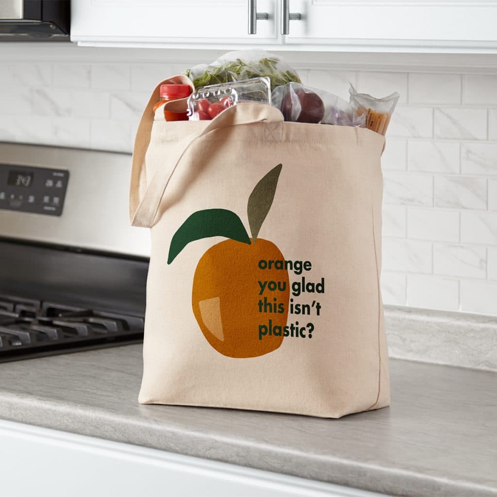 Everyday canvas tote bag full of groceries, featuring an "Orange you glad this isn't plastic?" design.