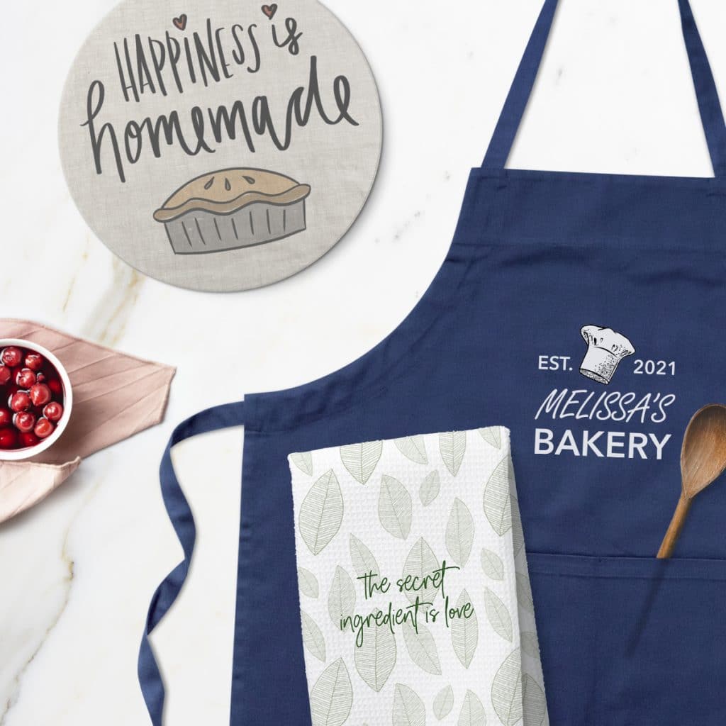 Flat lay image of kitchen accessories including a tea towel, navy blue apron, and trivet