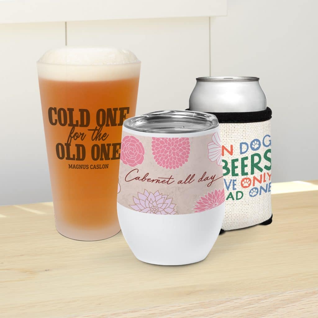Image showcasing a drinkware collection, including a pint glass, insulated wine tumbler, and can with cloth can cooler