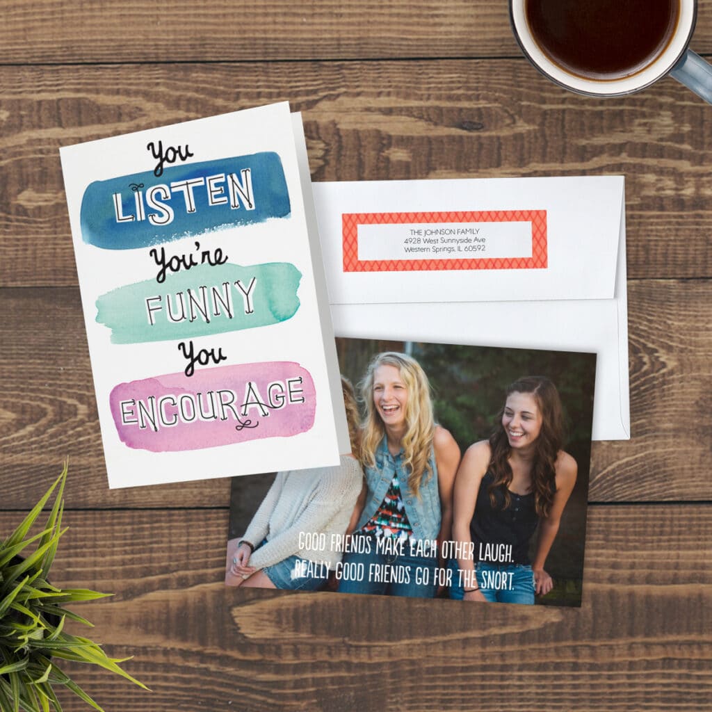 Image of two personalized greeting cards featuring friendship sentiments with an envelope on a tabletop. Next to them is a coffee cup and a houseplant.