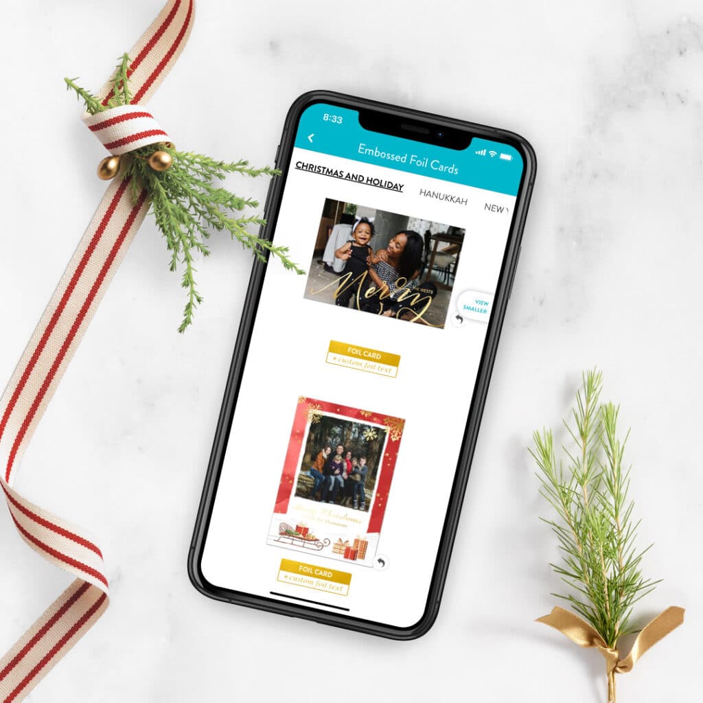 foil cards shown in the app on a phone, with holiday greenery