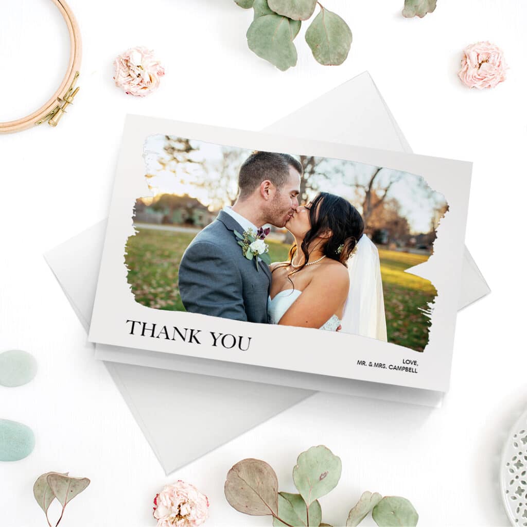 A thank you wedding card with an image of the happy couple kissing