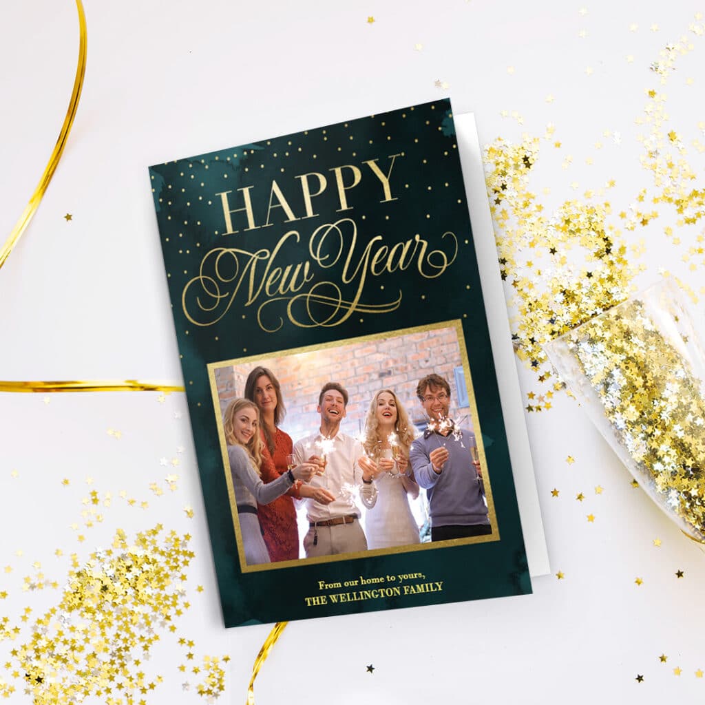 A happy New Year greeting card placed on a table full of shiny golden stars
