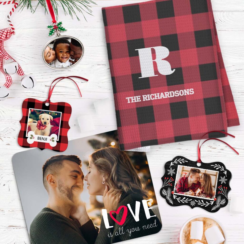 A selection of Christmas ornaments next to a placemat with a couples image and a personalized kitchen towel
