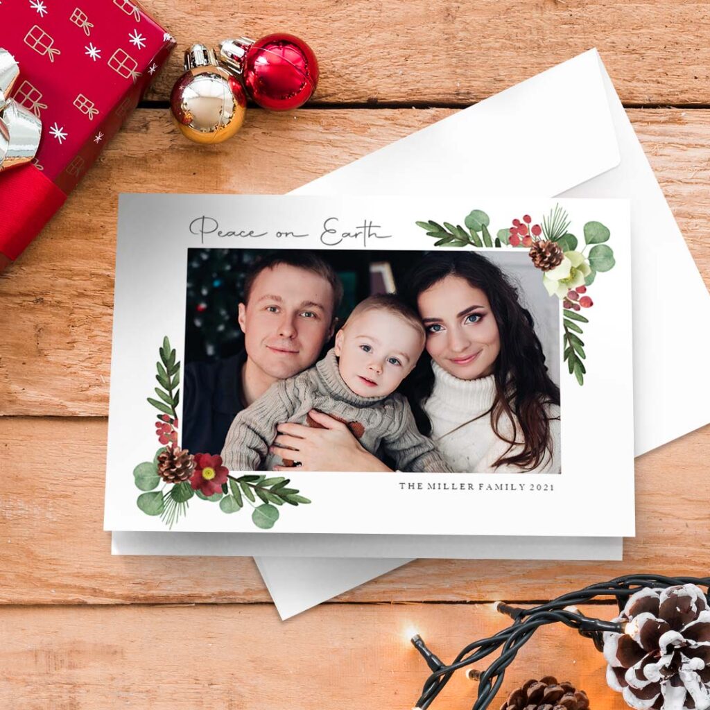 a Merry Christmas greeting card presented on a surface with Christmas gift, ornaments and lights