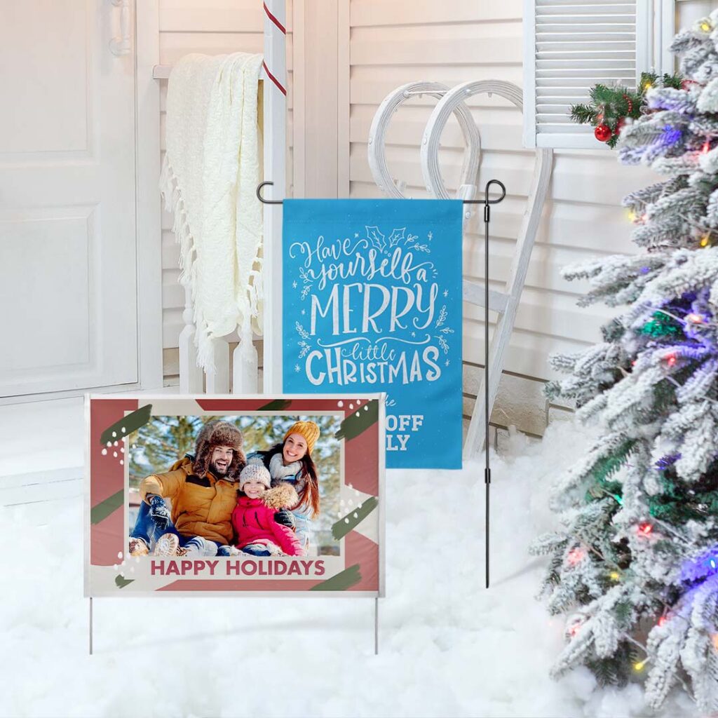 a Christmas yard sign and garden flag featured in a snowy front yard