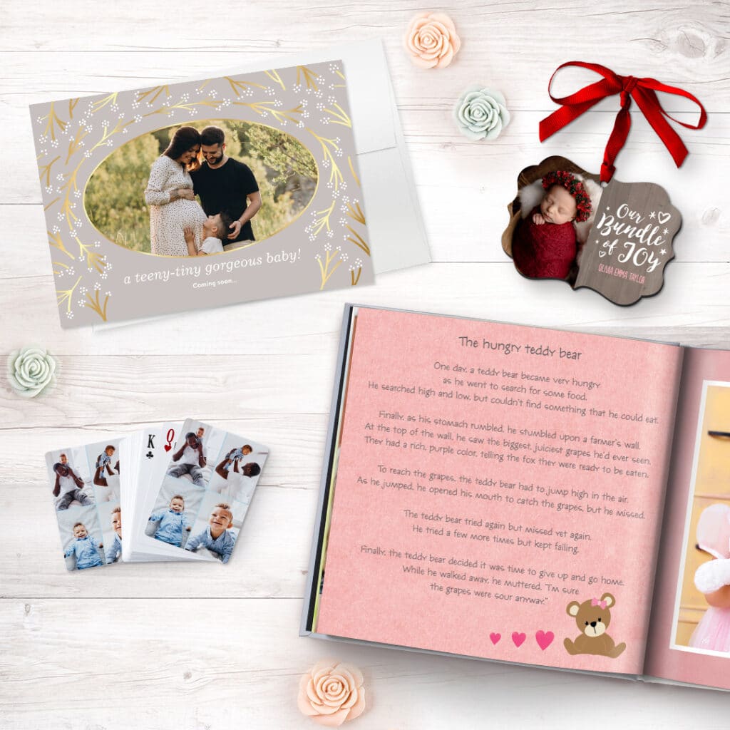 Variety of custom baby cards + gifts on a white surface with roses