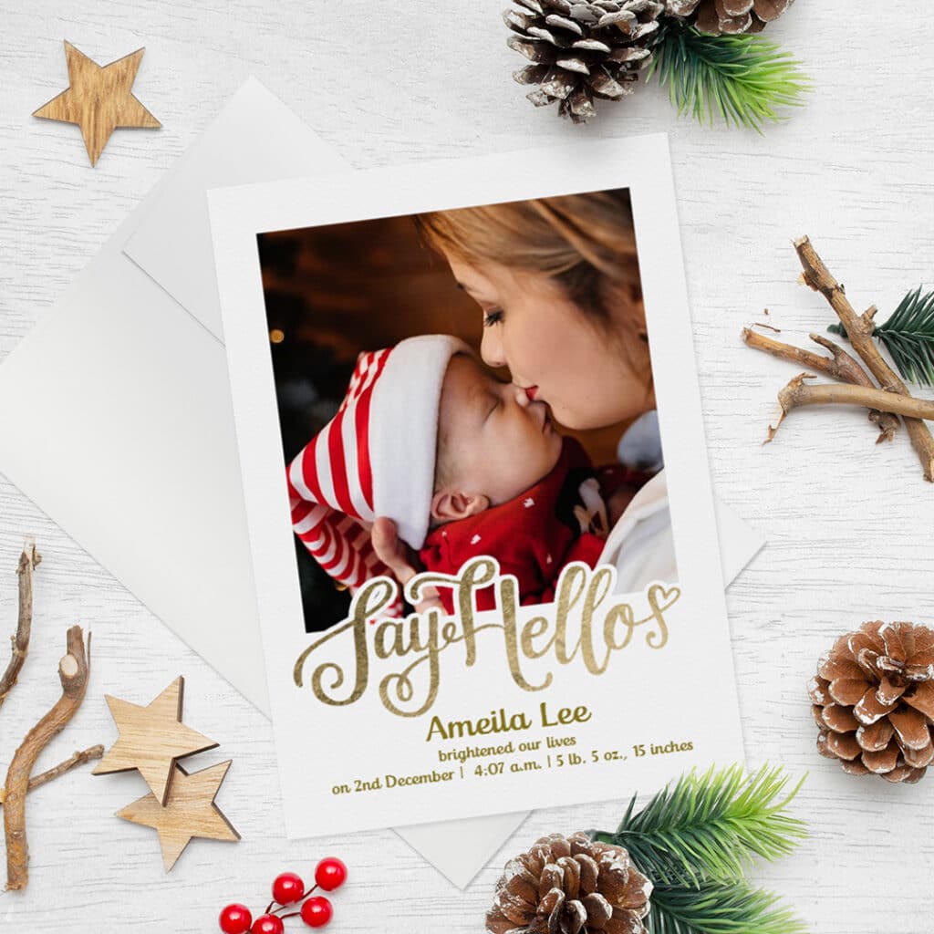 Say hello birth announcement card. Welcoming Christmas baby card on a surface with Christmas pine cones