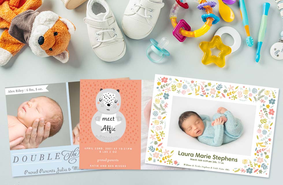 A selection of personalized baby announcement cards laying on a table with baby items